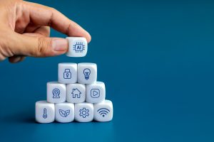 AI technology and smart home technology concepts. Artificial intelligence icon in human hand put on top of triangle shape blocks stack with home digital management control symbols on blue background. AI technology and smart home technology concepts. Artificial intelligence icon in human hand put on top of triangle shape blocks stack with home digital management control symbols on blue background.